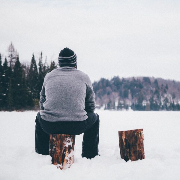 Grey wool sweater and knit hat seen from behind on a snowy lake shore