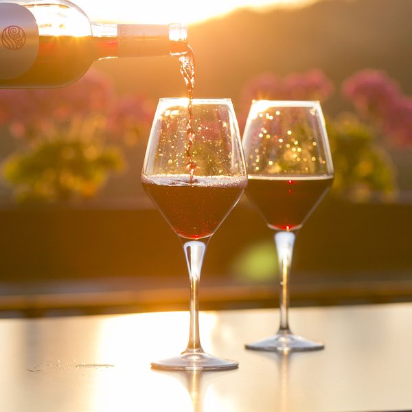 Red wine poured into two glasses in golden evening light