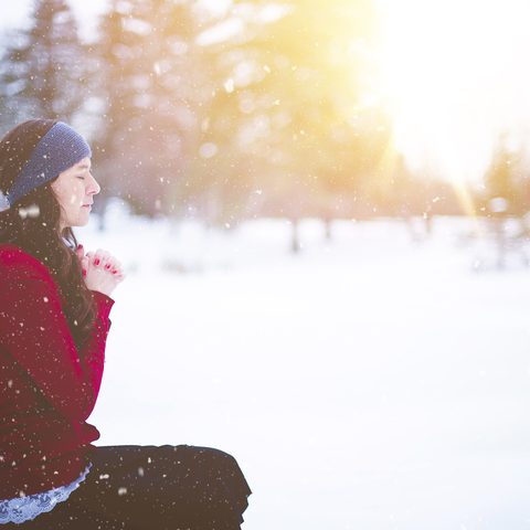 Woman in a red knit sweater sitting in the snow