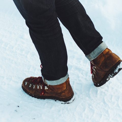 Brown leather boots stepping through deep snow