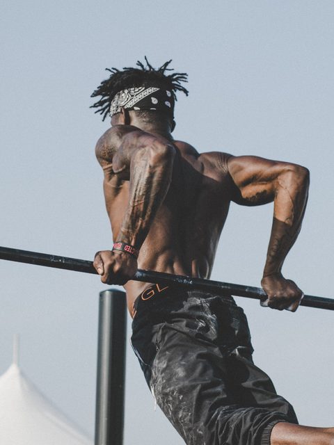 A man doing dips on outdoor parallel bars against a pale sky