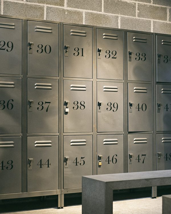 Rows of grey metal lockers and a bench in a gym changing room