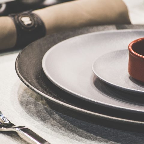 Stacked dinner plates and a rolled napkin set on a table